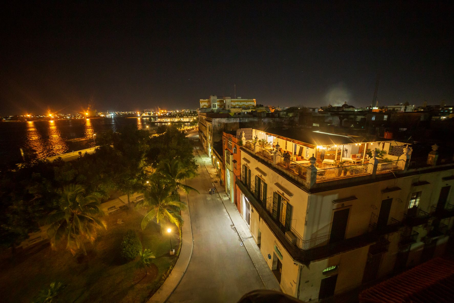 Lit rooftop terrace of a private Havana guesthouse overlooking the bay at night